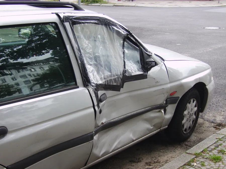 Yan kısmında çarpma hasarı olan gri station wagon